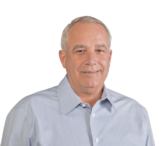 Portrait of a man with short gray hair, wearing a light blue button-down shirt. He is smiling and is set against a plain, dark background.