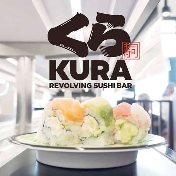 A plate of sushi with various toppings sits on a conveyor belt at Kura Revolving Sushi Bar. Above, the Kura logo and text read, "Kura Revolving Sushi Bar," with stylized Japanese characters in the design.